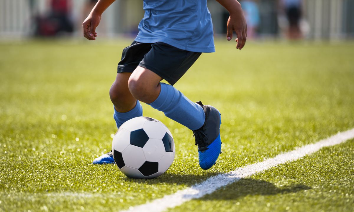 Young soccer player maneuvers a ball on the pitch.