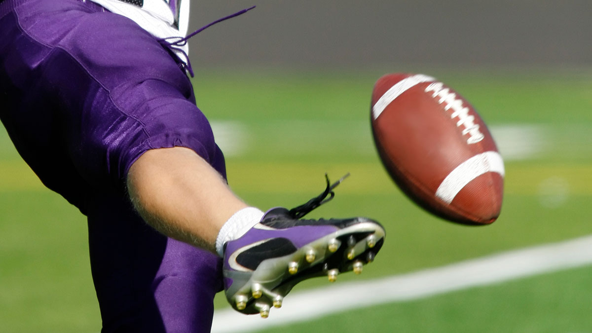 a football player kicking a ball.