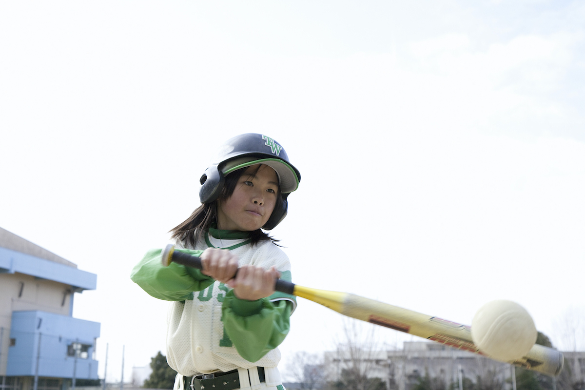 A child batter connects with the ball in the middle of a little league baseball game