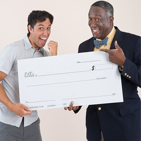 An older person in a very classy suit gives an excited younger person a novelty blank cheque.