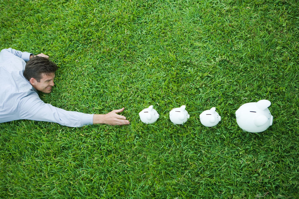 Someone crawls through the grass desperately trying to grab a series of increasingly large piggy banks ahead of him. 